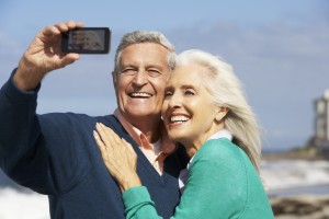 Senior Couple With Camera On Beach